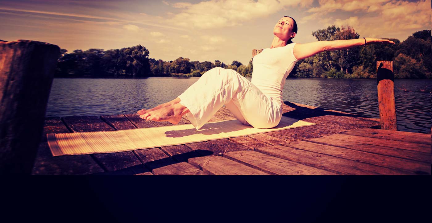 Image of a woman by the side of a lake, practicing yoga after private one to one yoga classes